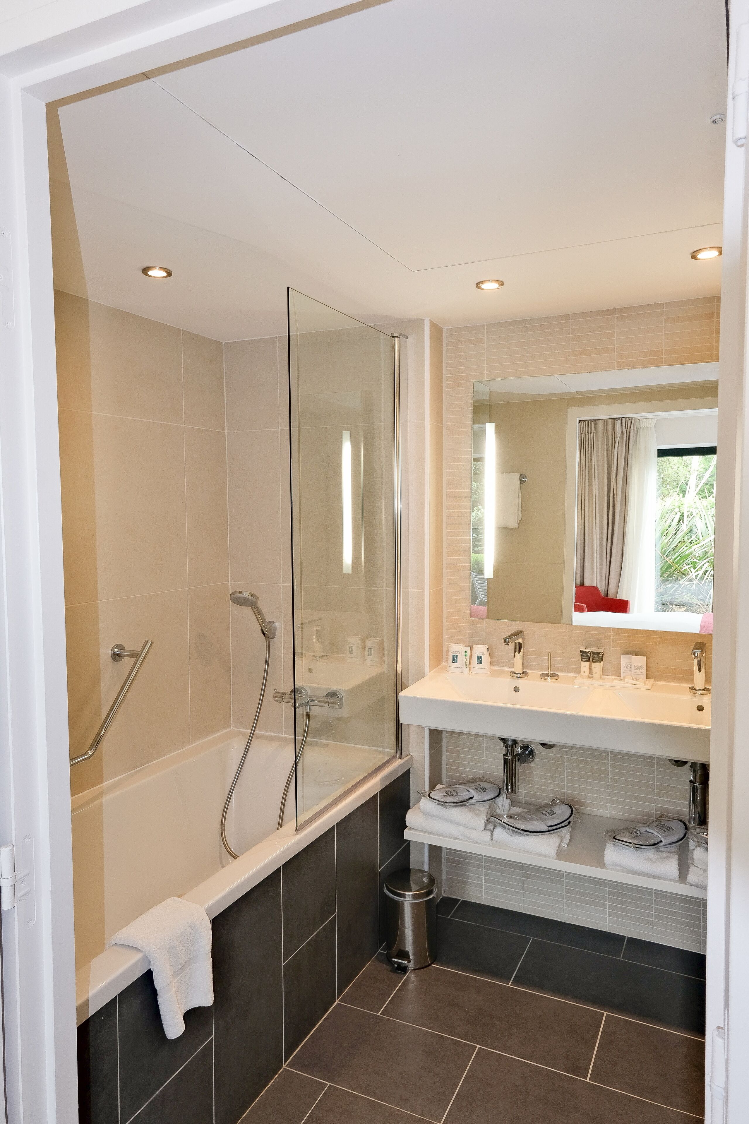 Une salle de bain moderne avec une douche à parois de verre, un meuble-lavabo doté de deux vasques et un grand miroir.