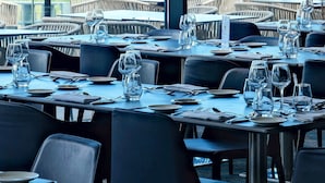 Un restaurante con mesas dispuestas para comer, con vista a una playa y al océano.