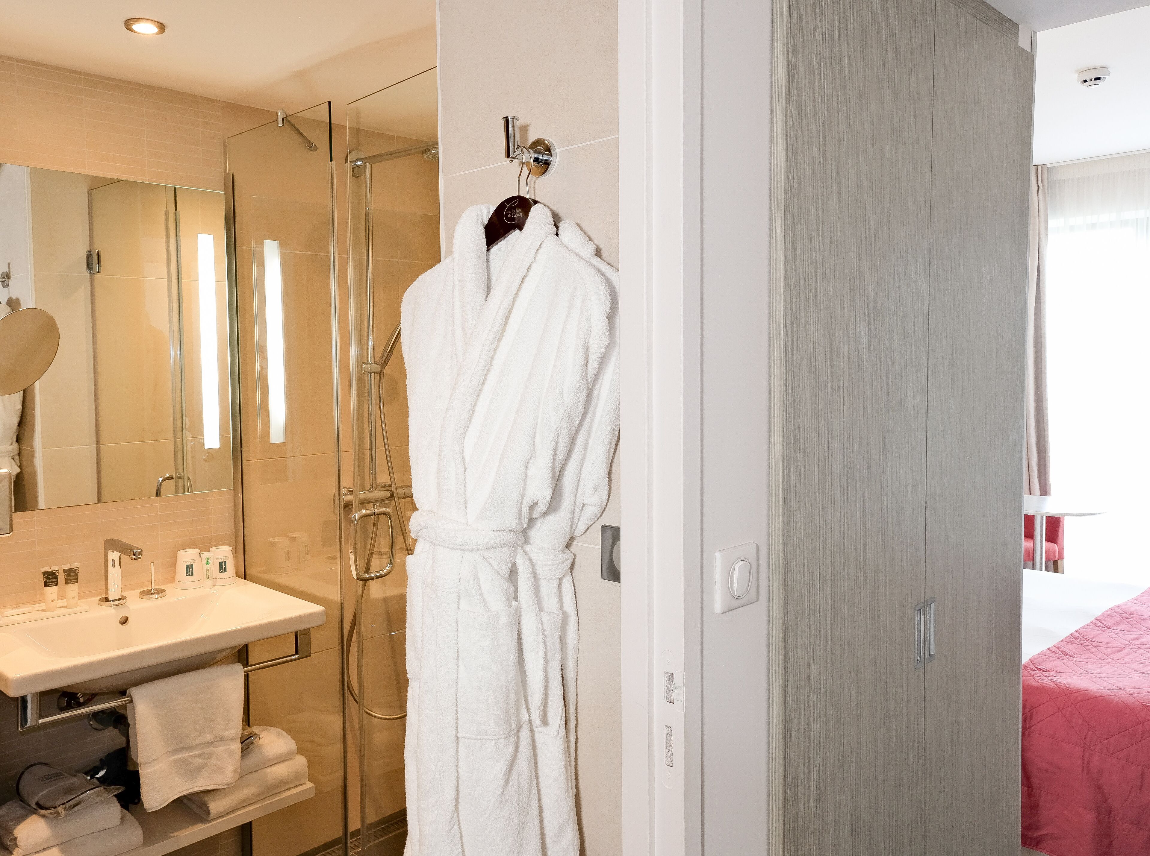 Une salle de bain moderne avec une douche à parois de verre, un lavabo blanc et un miroir.