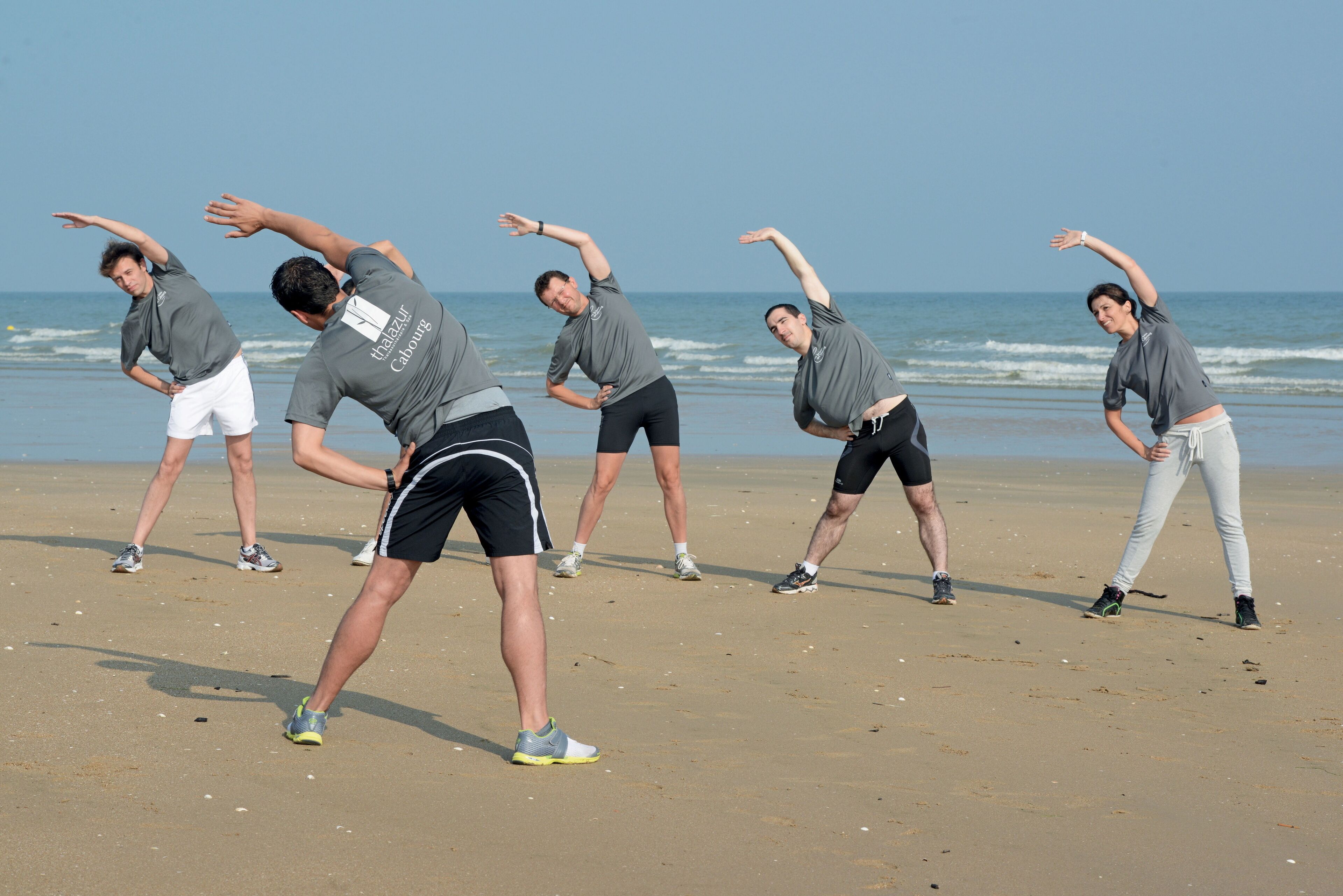 A beach with people stretching.