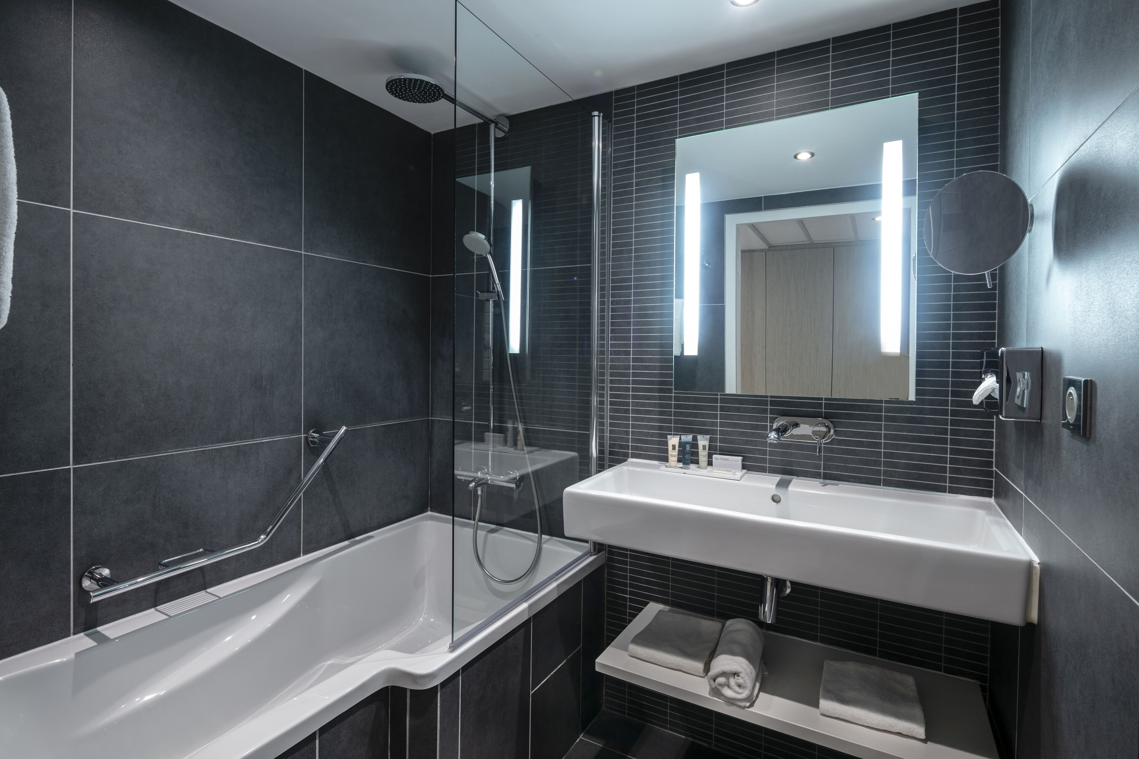 A modern bathroom with a glass-enclosed shower, a white sink, and a mirror.