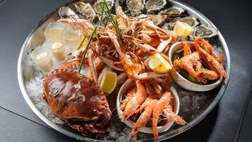 A seafood platter with shrimp, oysters, and a crab on ice.