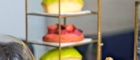 A dessert display with a glass dome cover and a three-tiered stand with various pastries.
