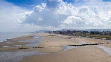 A beach with a rocky breakwater, a sandy shore, and buildings in the background.