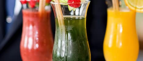 Trois cocktails servis dans des verres avec des pailles, décorés de tranches de fruits et d’une fraise.
