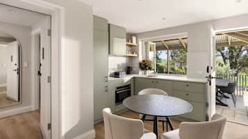 A modern kitchen with a round dining table and chairs, light green cabinets, and a view of the outdoors.