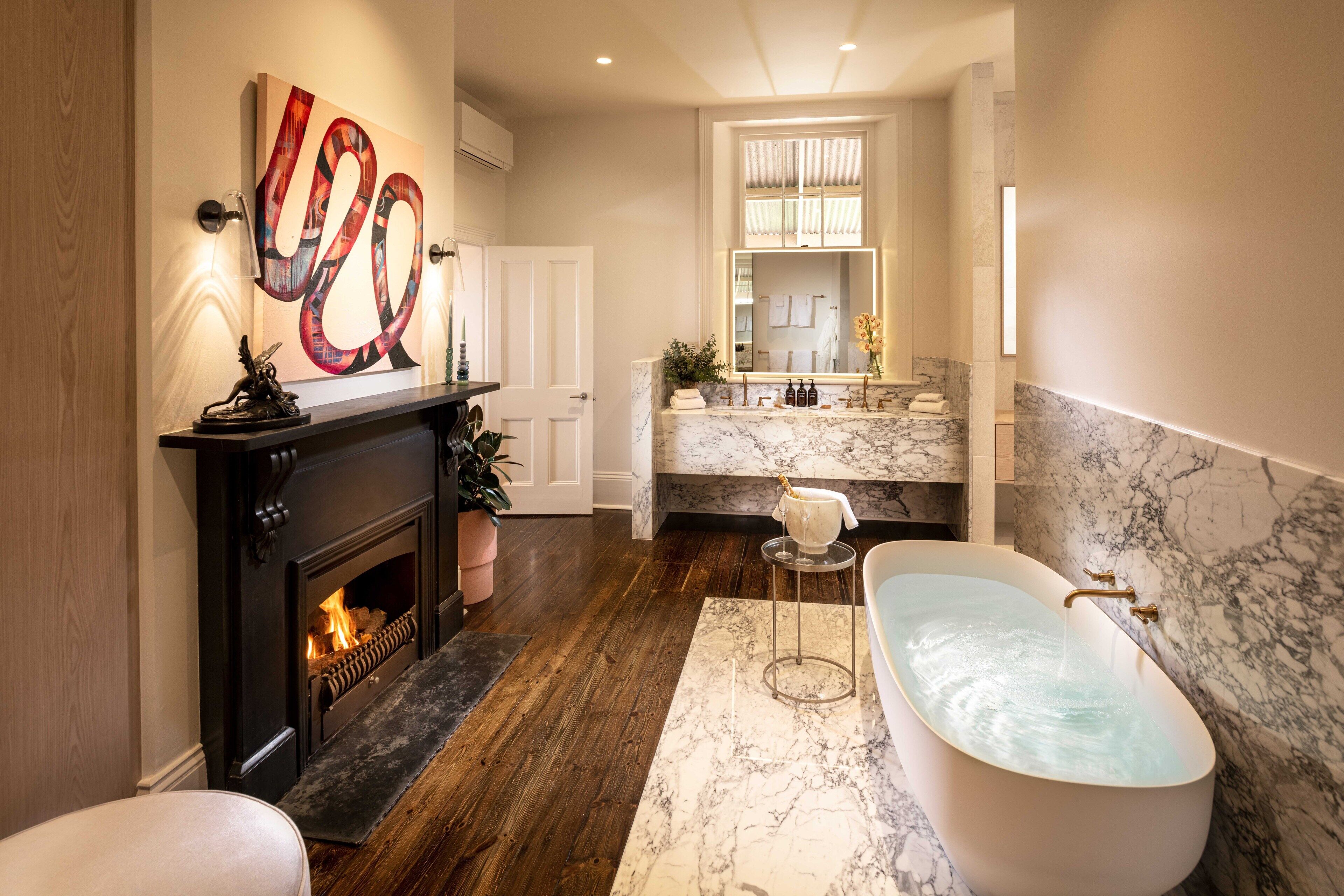 Une salle de bain moderne avec une baignoire sur pieds, un lavabo en marbre et une cheminée.