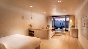 Una habitación de hotel moderna con una cama grande, una zona de estar con vistas y un escritorio pequeño.