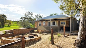 A building with a brick facade, a covered porch, and a fenced outdoor area with steps leading to a water feature.