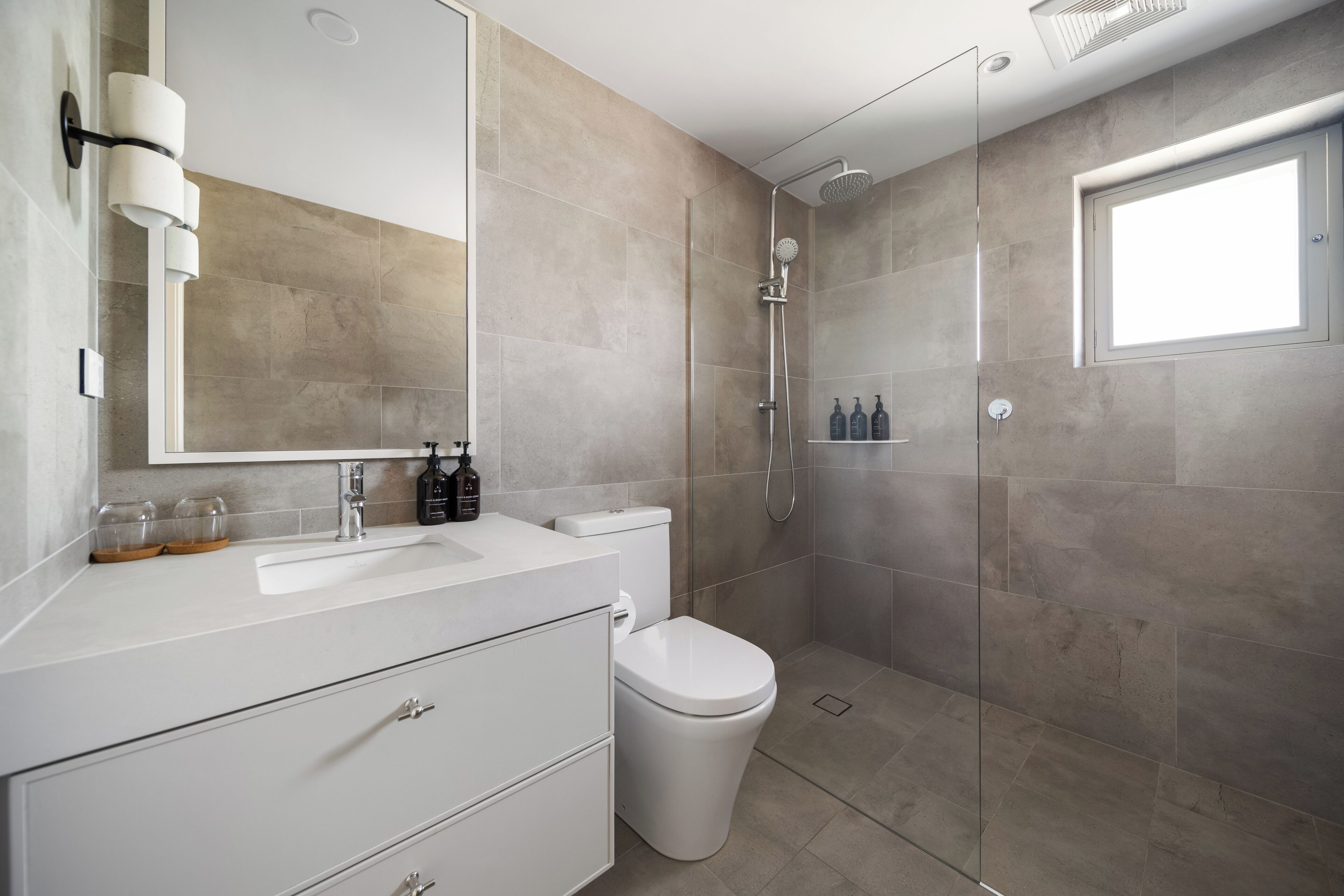 A modern bathroom with a glass shower enclosure, a white sink, and a toilet.