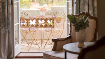 A room with a balcony, a table with chairs, and a potted plant.