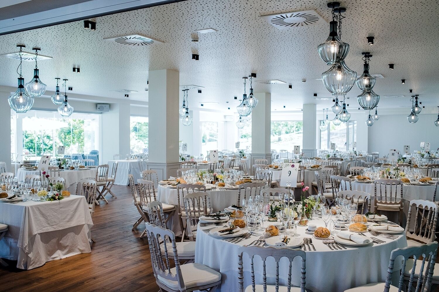 Un gran salón de banquetes con mesas redondas, manteles blancos y elegantes candelabros.
