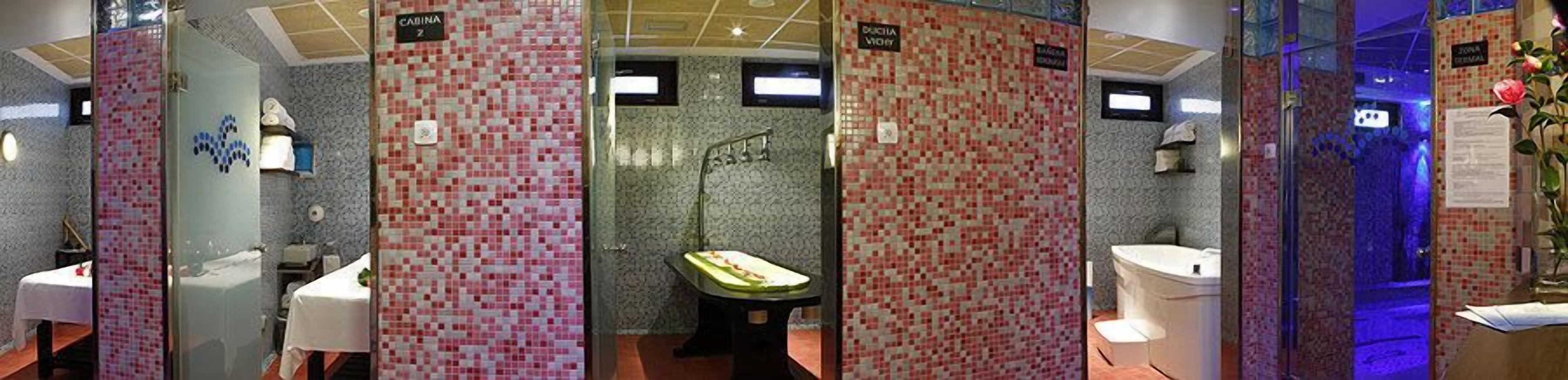 Un baño con paredes de mosaico, una bañera, un lavabo y una zona de ducha.