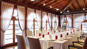 Una larga mesa de comedor preparada para una comida en una habitación con ventanas grandes y vigas de madera.