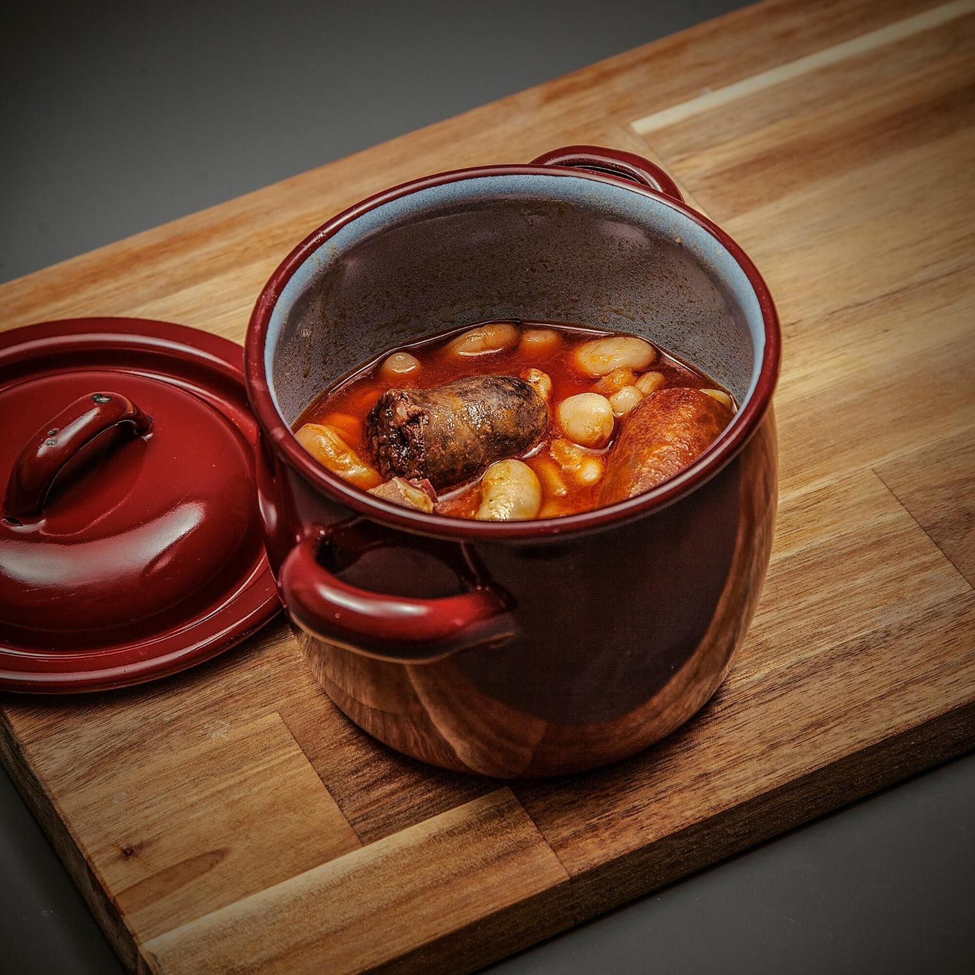 A red pot with a lid on a wooden surface.