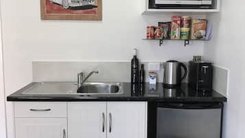 Una cocina compacta con un lavaplatos de acero inoxidable, un microondas, una cafetera y un refrigerador.