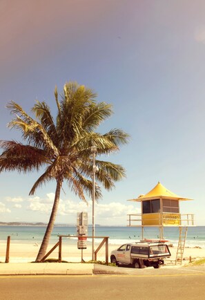 Una torre de salvavidas, una palmera y un vehículo de socorristas en la playa.