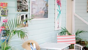A porch with a white table and chairs, a hat, and a potted plant. - La Costa Motel (Bilinga)