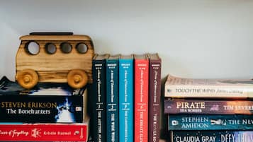 Dos estanterías repletas de libros y un autobús de juguete de madera.