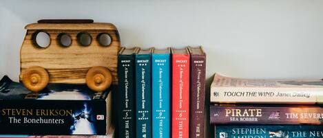 Two bookshelves with a variety of books and a wooden toy bus.