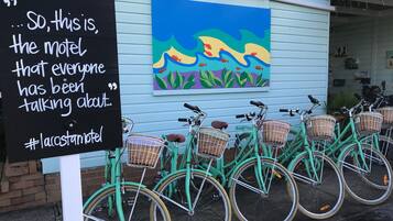 A sign with a quote, a colorful mural, and a row of green bicycles with baskets.
