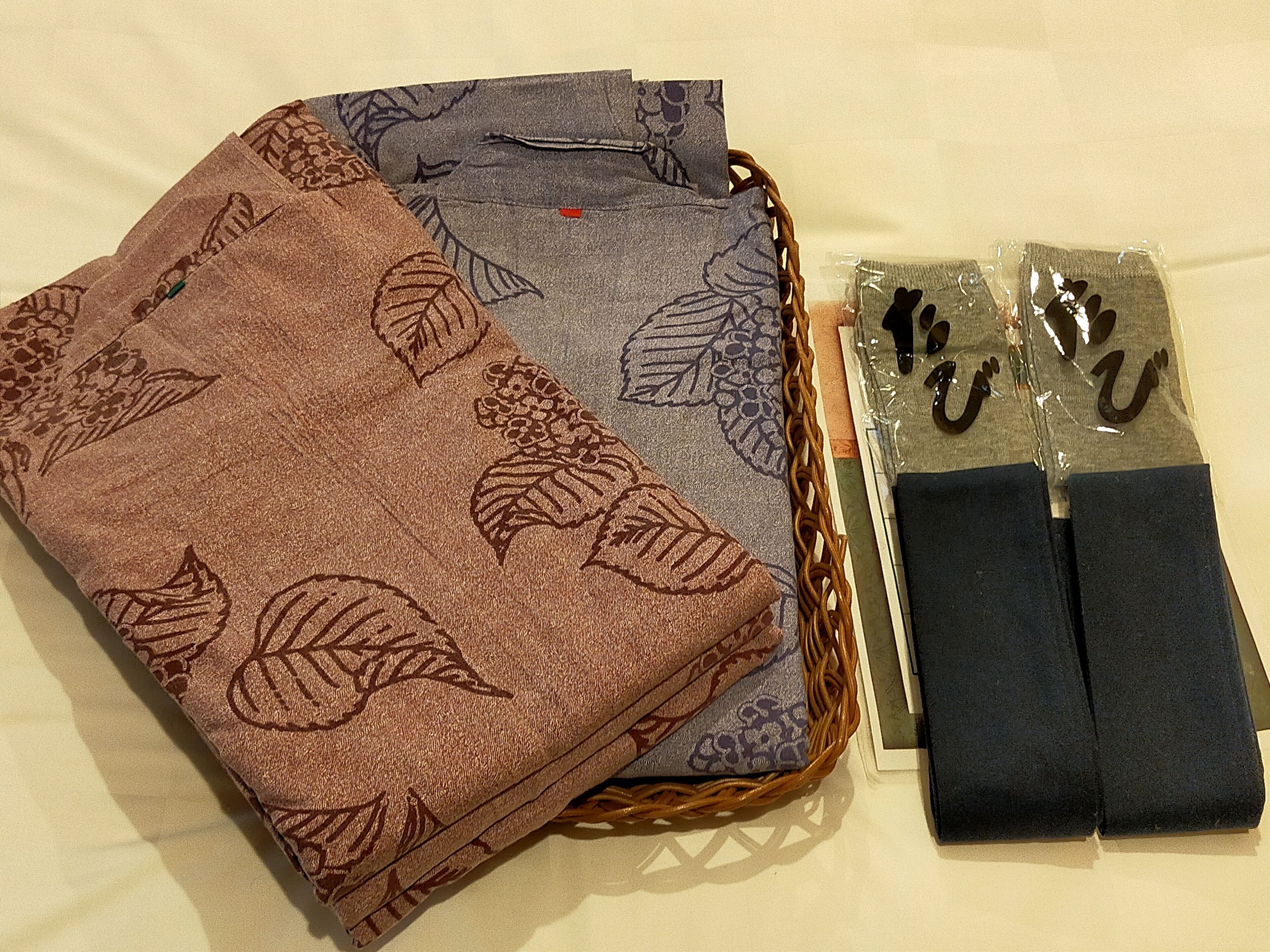 A basket with folded towels and a pair of slippers.