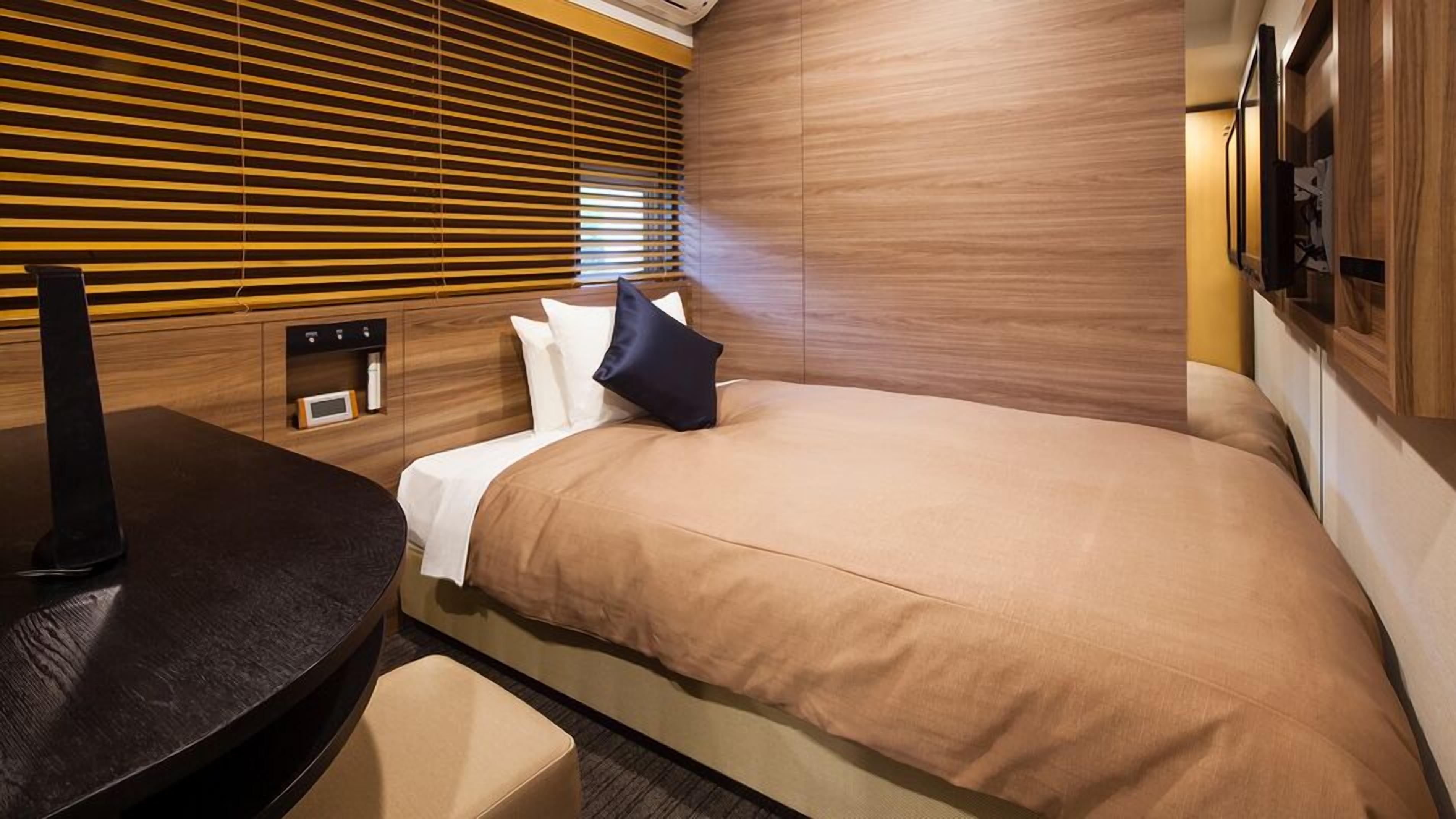 Ein modernes Hotelzimmer mit Bett, Schreibtisch und Fernseher.
