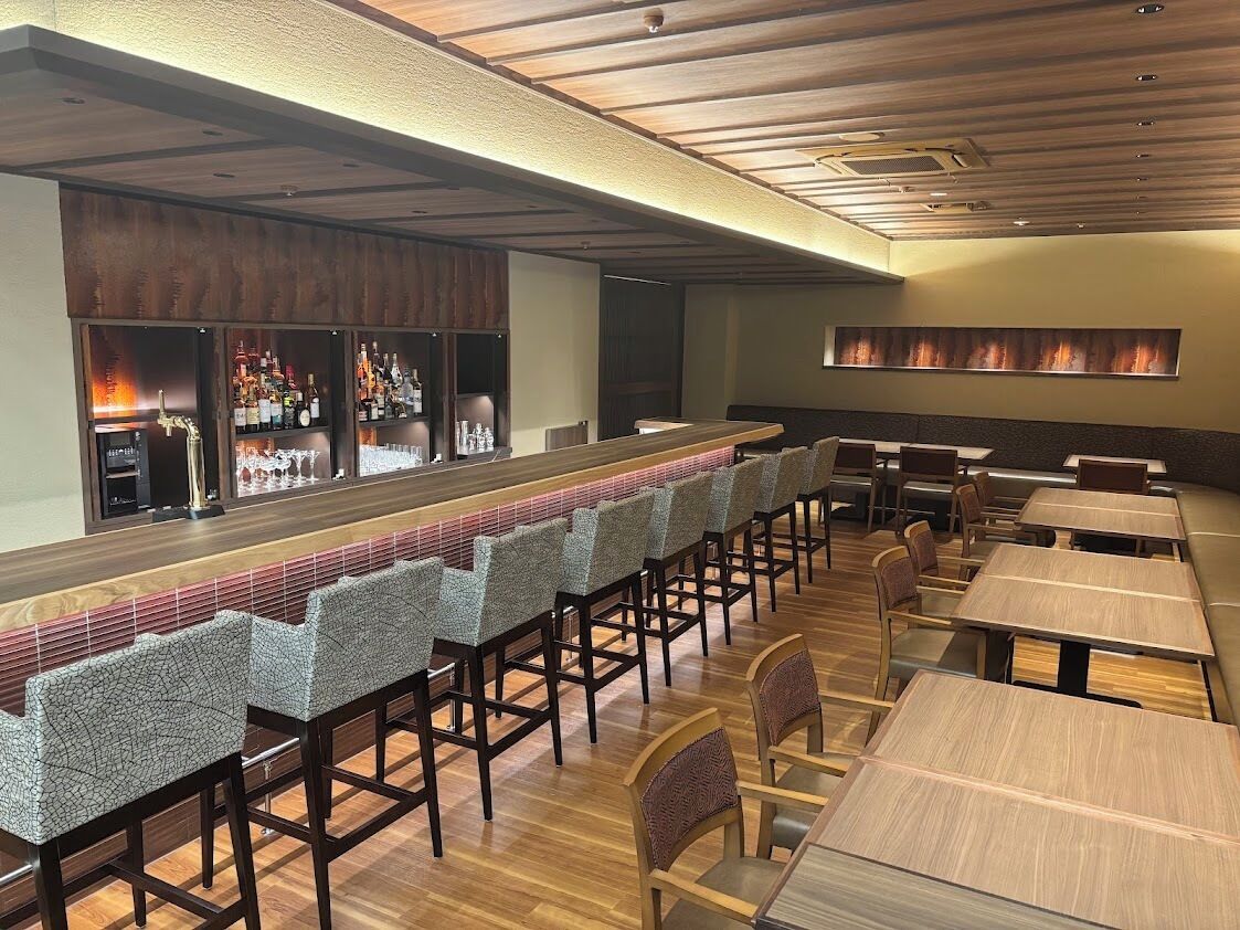 A restaurant with a long bar, high stools, and booths.