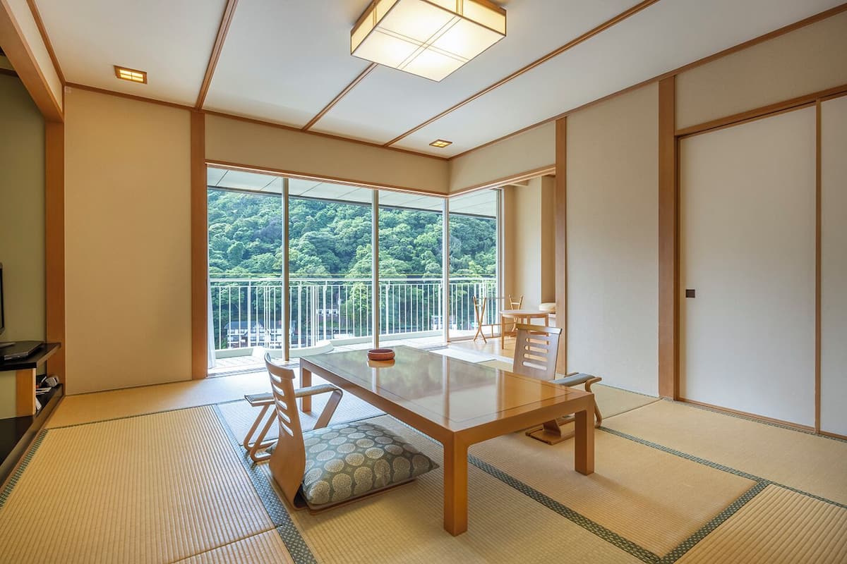 Um quarto japonês tradicional com tatames, uma mesa baixa e portas deslizantes.