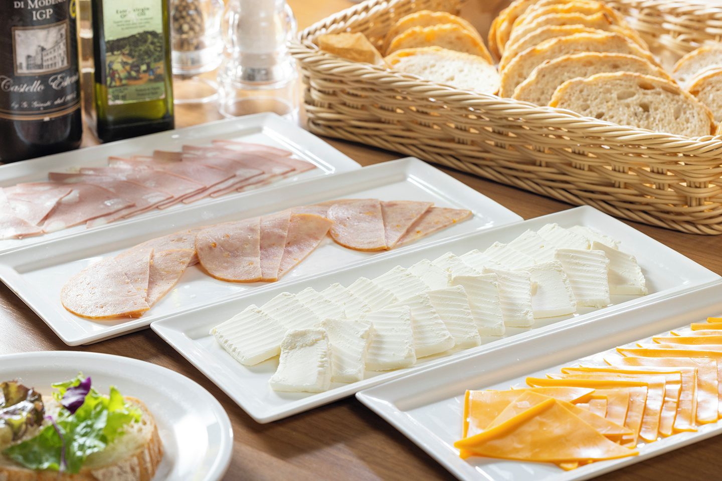 A table with various food items including sliced meats, cheeses, and bread.
