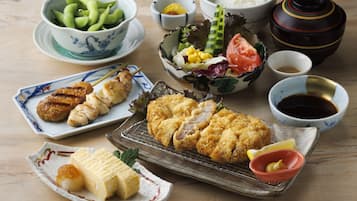 Variedad de platos japoneses, incluyendo tempura, sashimi y un tazón de edamame.