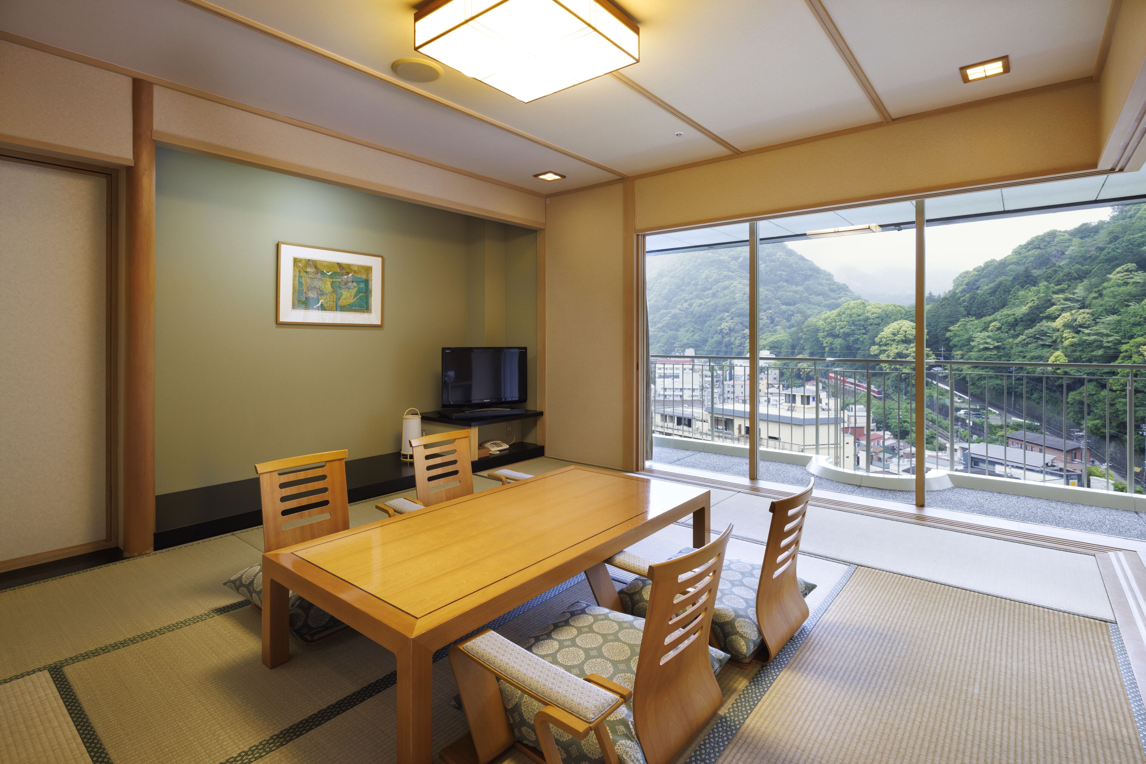 A traditional Japanese-style room with tatami flooring, a wooden dining table, and a television.