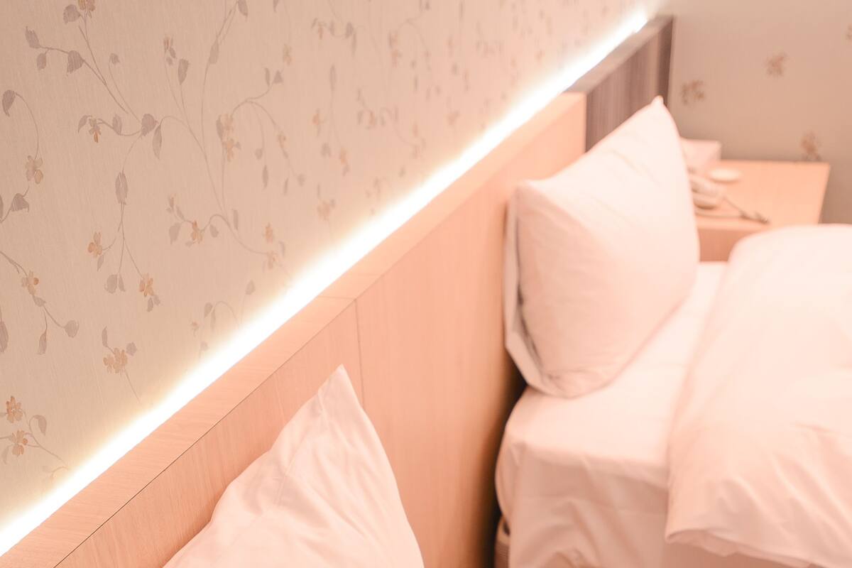 Un dormitorio con cabecera, dos camas y una mesita de noche con lámpara.