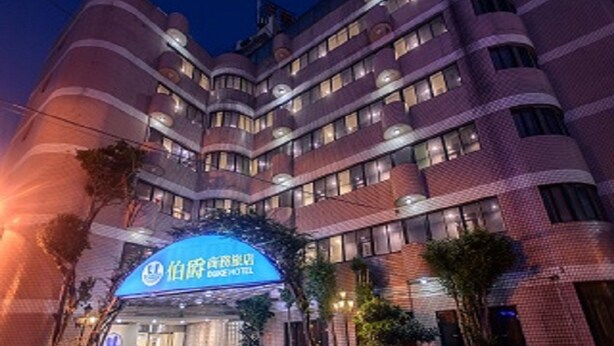 Een hotel met meerdere verdiepingen, met een groot blauw bord waarop 'Dahua Hotel' staat.