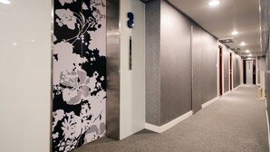 Een gang met een deur met bloemenprint, een inbouwlift en een tapijtvloer.