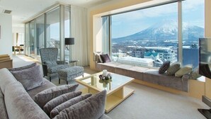 A modern hotel room with a large window offering a view of a mountain and cityscape. - Chalet Ivy Hirafu (Kutchan)