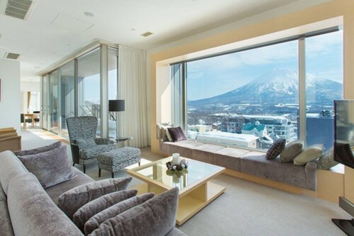 A modern hotel room with a large window offering a view of a mountain and cityscape.