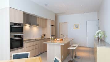A modern kitchen with built-in appliances, a central island with bar stools, and a small dining area.