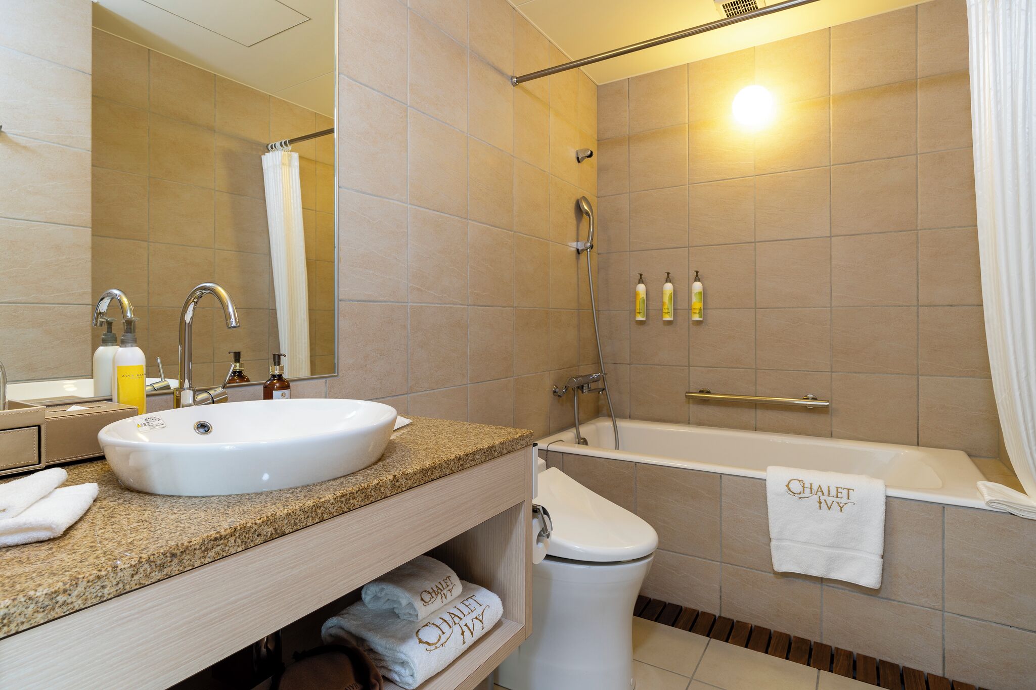 A bathroom with a sink, mirror, toilet, and bathtub.