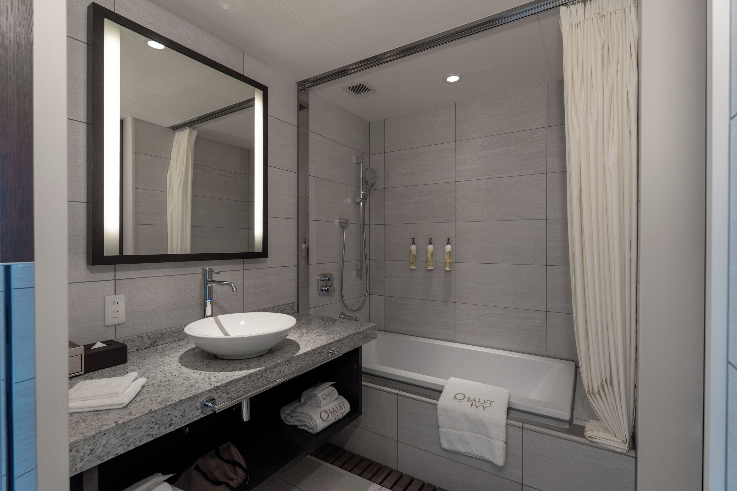 Un baño moderno con un espejo grande, un lavabo, una ducha y una bañera.