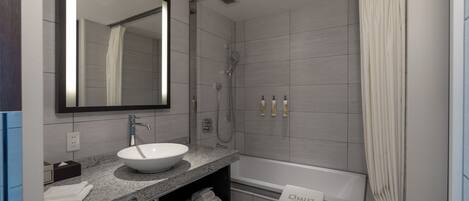 Un baño moderno con un espejo grande, un lavabo, una ducha y una bañera.