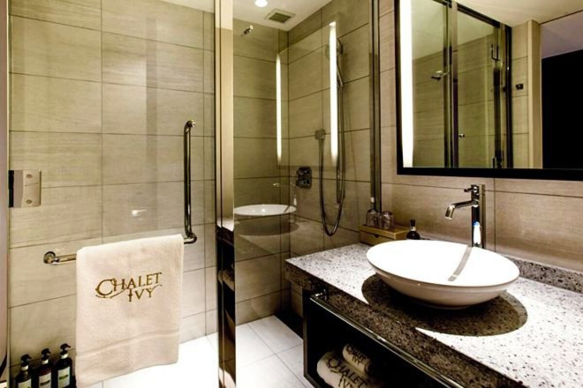 A modern bathroom with a glass-enclosed shower, a freestanding sink, and a large mirror.