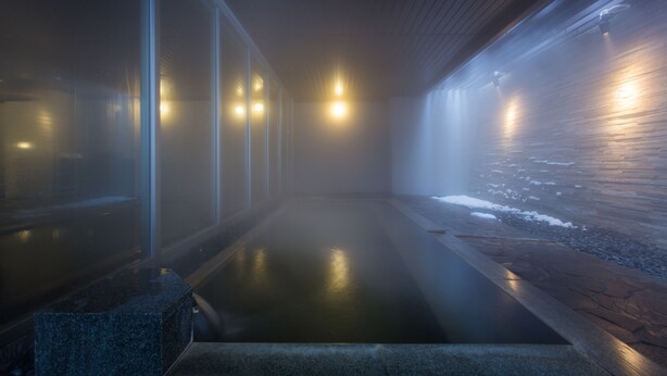 A modern indoor pool area with clear glass walls, a wooden floor, and a stone ledge. - Chalet Ivy Hirafu (Kutchan)