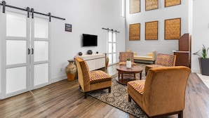 Un salon moderne doté d’une grande fenêtre, d’un téléviseur à écran plat et d’un coin salon avec des fauteuils à motifs et une table basse.