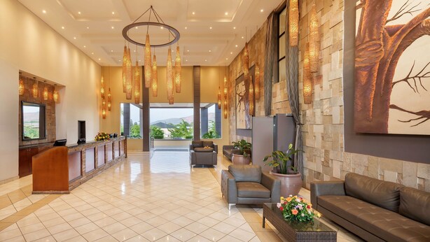 A spacious lobby with a reception desk, seating area, and a large window offering a view of the outdoors.
