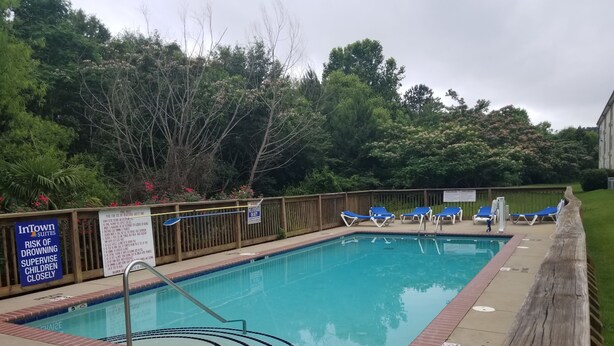 Piscina com cadeiras de sol azuis e cerca de madeira.