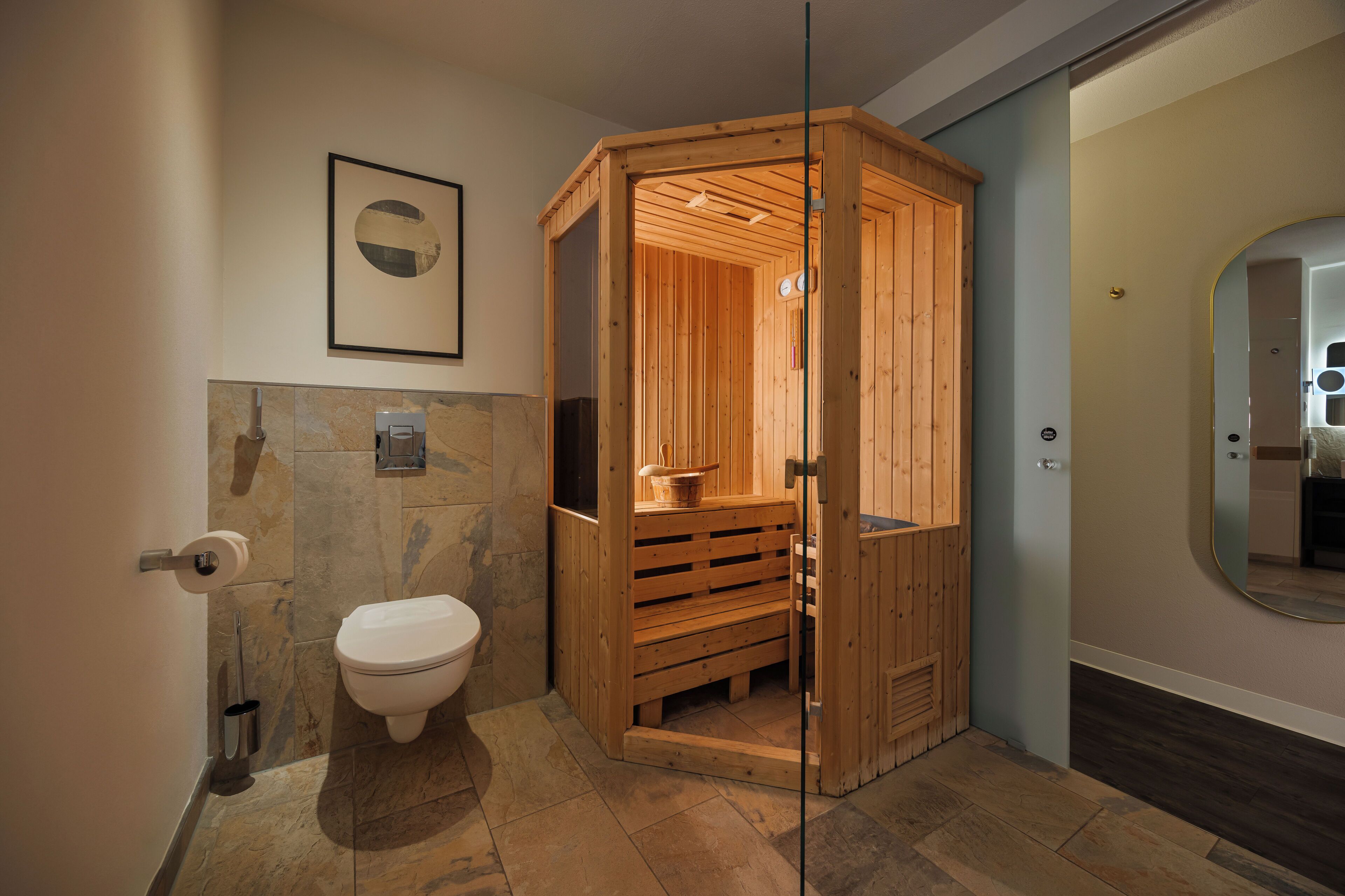 Een moderne badkamer met een houten sauna, toilet en een vloer van marmeren tegels.