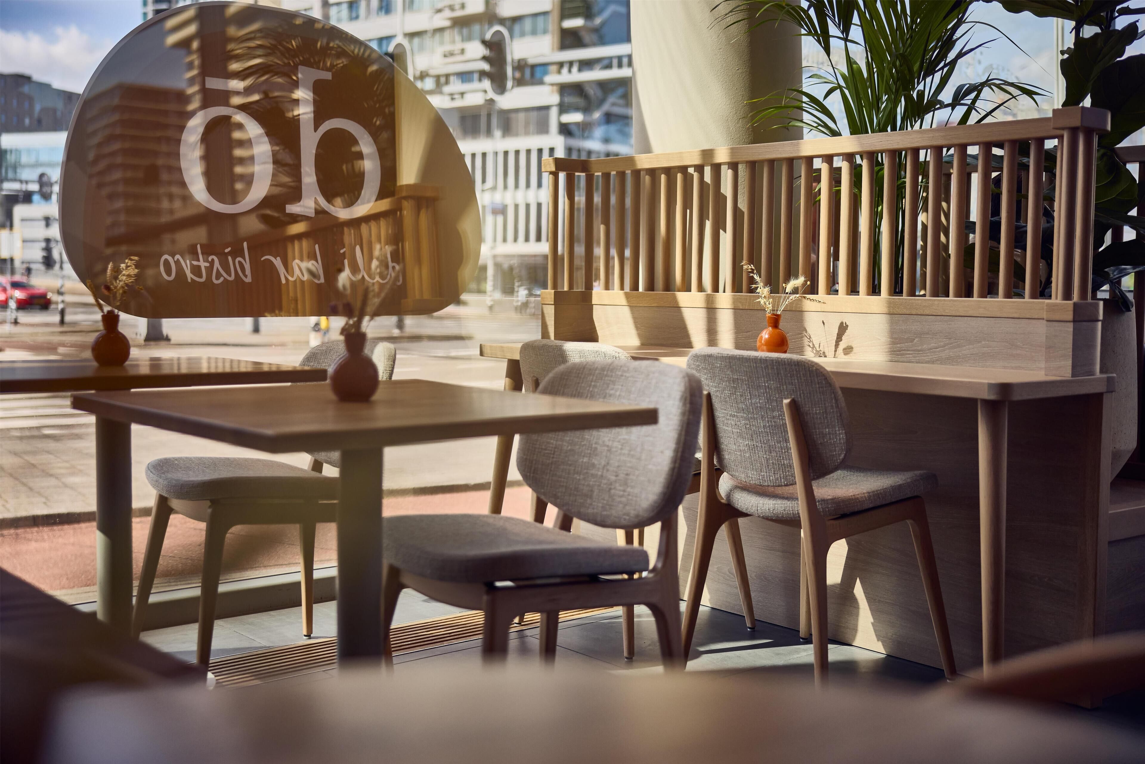 Een terras met een houten tafel en stoelen, een grote decoratieve spiegel en een houten leuning.