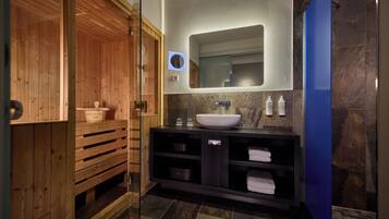 A modern bathroom with a wooden sauna, a large sink, and a mirror above it.