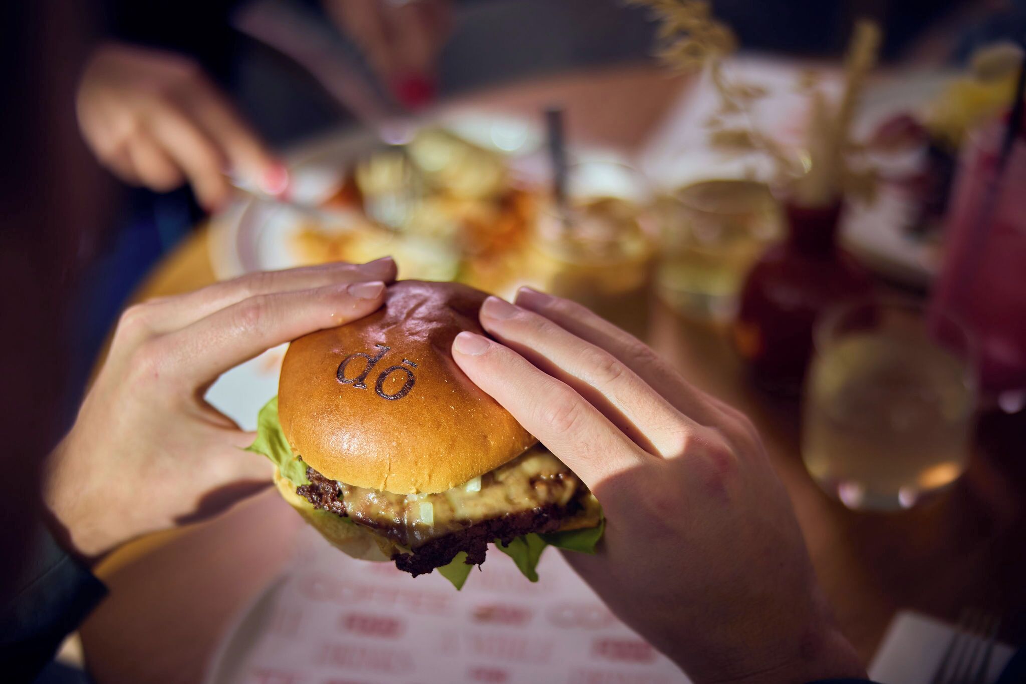 Una persona sosteniendo una hamburguesa con un logotipo visible en el pan.